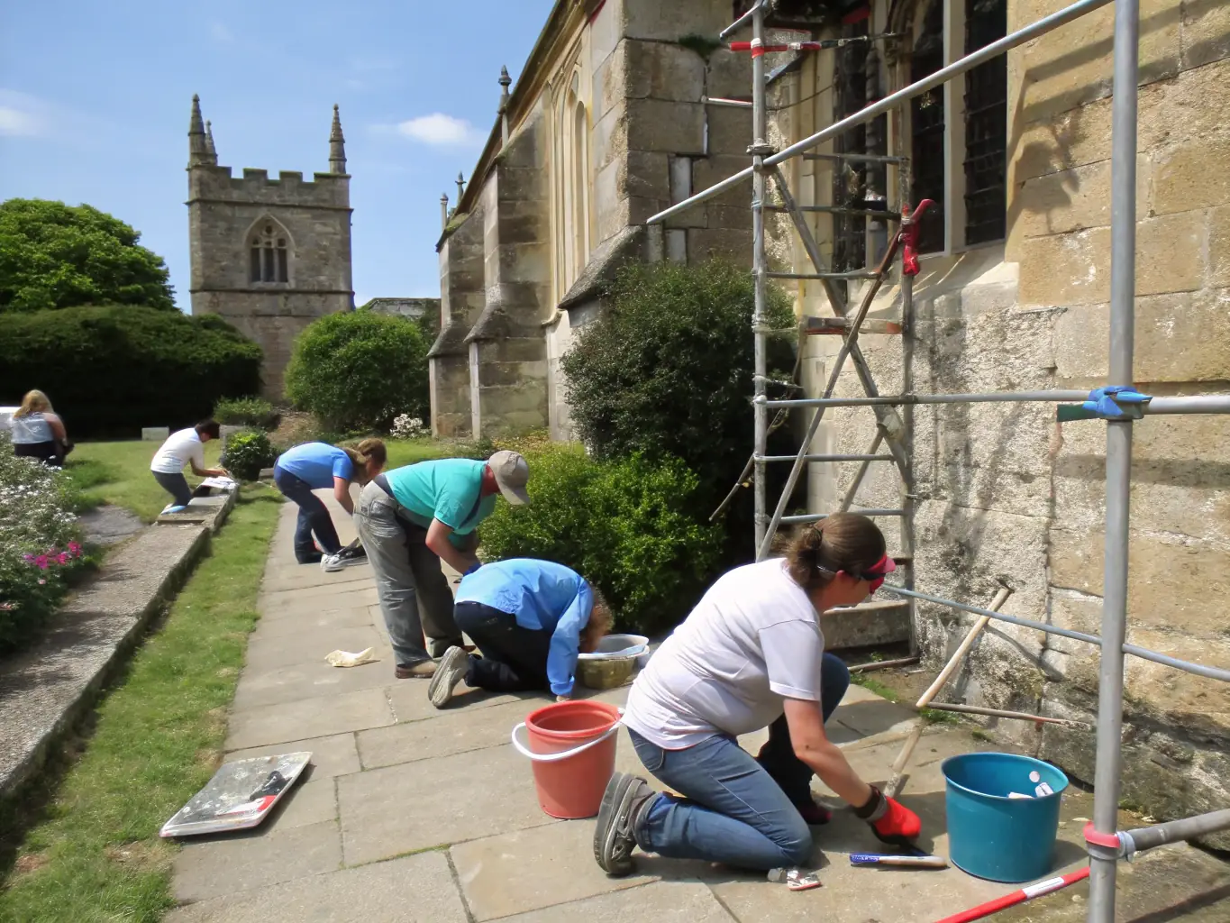 A group of volunteers working together to restore a historic watermill, focusing on the intricate details of the mill's machinery and structure.